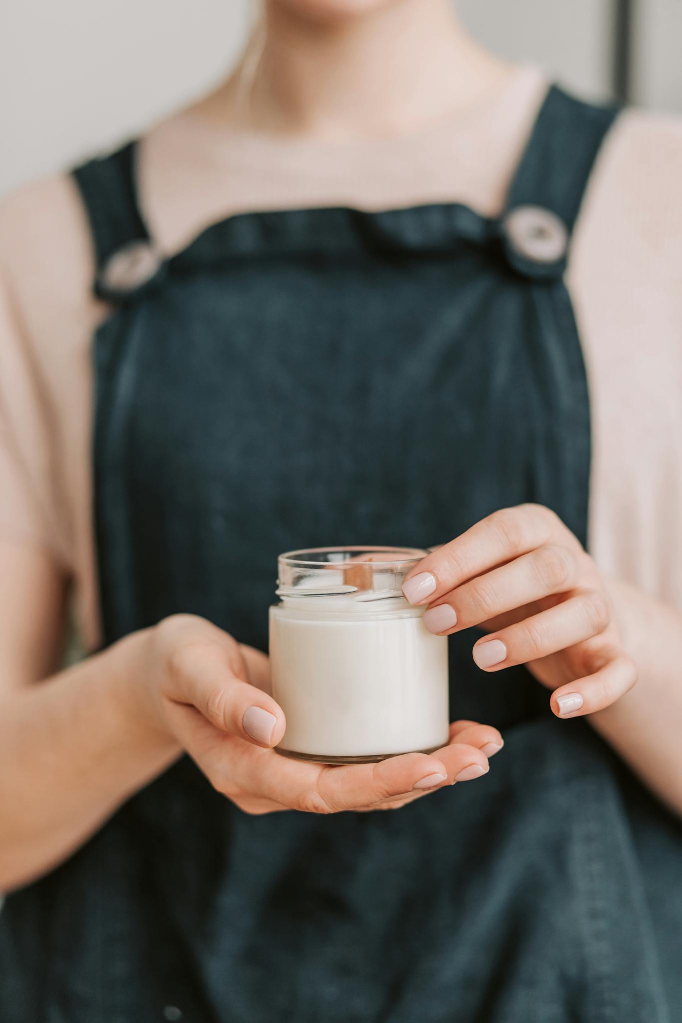 Close-up of woman holding a glass jar with a handmade candle. Perfect for small business and crafting themes.